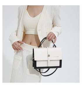 Detail view of the black and white contrast leather bag with gold metal buckle and logo