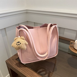 Grand sac cabas en similicuir rose avec un joli pendentif ours en peluche sur table