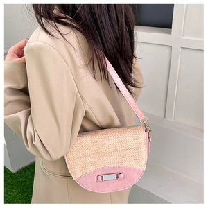 Detail of pink leather and straw crossbody bag with silver clasp and chain strap