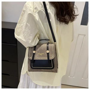 Close-up of retro mixed-material crossbody bag with gold rivets and metallic clasp