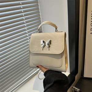 Petit sac à dos beige en cuir plissé pour femme avec boucle papillon argentée