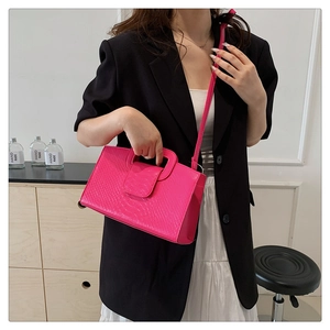 Detail of pink crocodile embossed leather handbag with adjustable crossbody strap