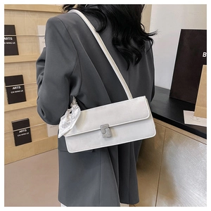 Détail du sac baguette blanc avec boucle en strass et foulard en soie sur un tailleur