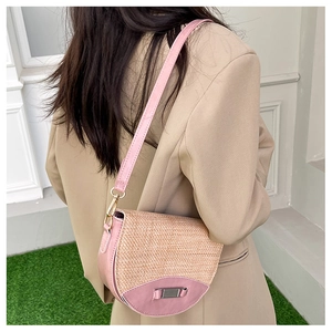 Crossbody saddle bag in pink and beige weave, worn with a blazer over green grass