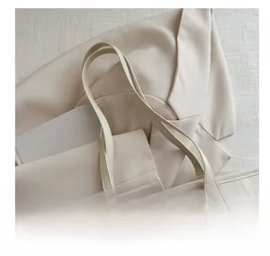 Detail of beige tote bag featuring textured faux leather and slim shoulder strap design