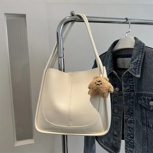 Grand sac fourre-tout crème avec breloque d'ours suspendu sur un cintre avec denim