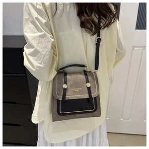 Detail of retro crossbody bag showing rivet edges and gold brand logo on matte material