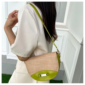 Detail view of woven straw and green leather saddle bag with silver metal buckle closure