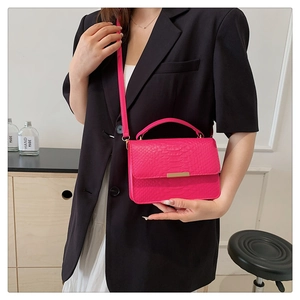 Detail of hot pink crocodile pattern crossbody bag with golden metal hardware buckle
