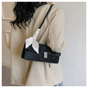 Detail of black suede shoulder bag with rhinestone buckle and silk scarf decoration