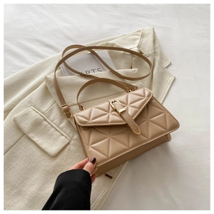 Detail of khaki quilted shoulder bag with gold clasp on cream blazer background