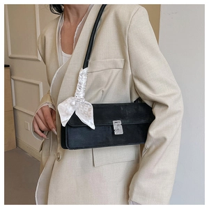 Détail du sac baguette noir mat avec boucle en cristal et poignée ornée d'un foulard