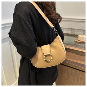Close-up of beige hobo bag with a polished gold horseshoe buckle and matte leather texture