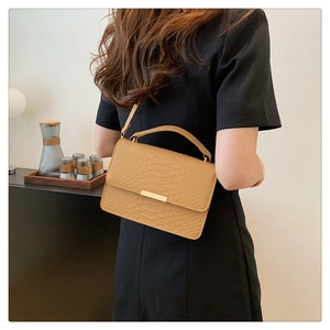 Crossbody view of a camel crocodile pattern handbag with elegant gold metal trim decoration