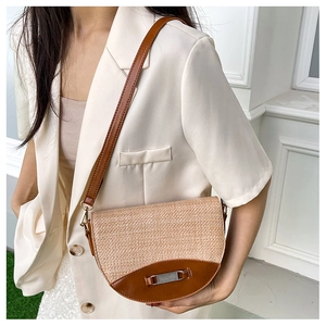 Detail of woven saddle bag with leather trim worn by model in white blazer