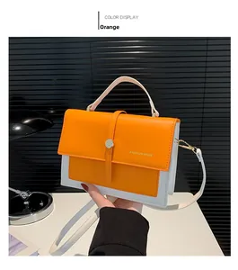 Detail of orange and white leather handbag with golden hardware and adjustable strap
