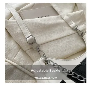 Detail of adjustable strap with silver buckle and letter print on white leather bag