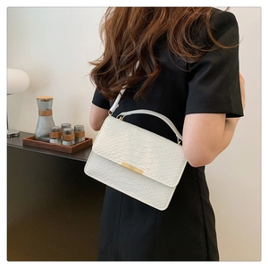 White faux crocodile leather handbag with elegant gold metal latch shown on a model