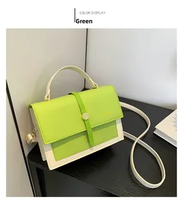 Close-up of green and beige crossbody bag with gold round clasp and handle detail