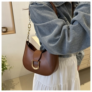Close-up of caramel hobo bag with gold U-shaped hardware and elegant chain strap