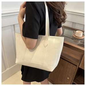 Close-up of white striped large tote bag with NESS logo on a minimalist interior background