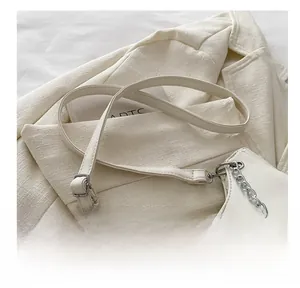 Close-up of white leather handbag featuring silver chain strap and mini letter patch