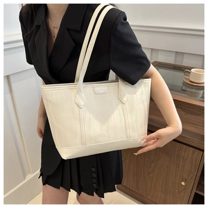 Detailed close-up of cream tote bag featuring embossed wave texture and brand logo tag
