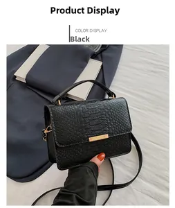 Detail of black faux crocodile skin texture and gold metal buckle on a small square bag