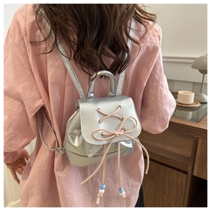 Close-up of silver mini backpack with pink bow ribbons and decorative beads