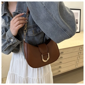 Close-up of brown crescent underarm bag with gold U-shaped buckle and chain strap