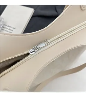 Close-up of smooth silver metal zipper and textured cream leather on the tote bag