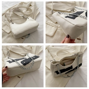Macro views of white canvas underarm bag with black lettering and silver chain strap