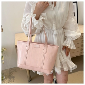 Detail of pink faux crocodile leather tote bag with elegant metallic logo and slim straps