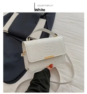 Detail of white faux snake pattern handbag with gold hardware and top handle