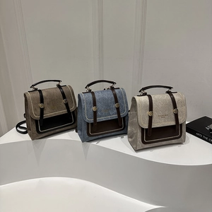 Three retro faux-leather backpacks in brown, blue, and taupe on white display stands