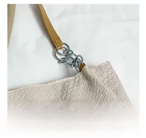 Close-up of beige snake-embossed leather texture with silver metal chain hardware detail