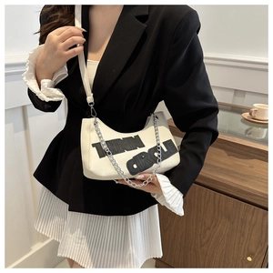 Detail showing the white crescent underarm bag with black TINN CIRCLE lettering and silver chain