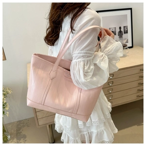 Detail of light pink tote bag featuring crocodile embossed texture and dual shoulder straps