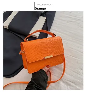 Detail of orange crocodile pattern crossbody bag with metal magnetic buckle and strap