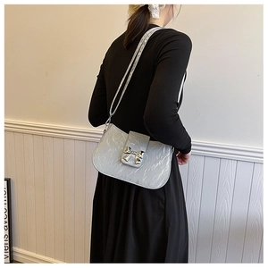 Details einer silbernen Metallic-Schultertasche mit dekorativer Schleifenschnalle und Kette
