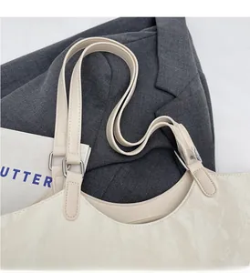 Detail of reinforced handles and silver metal D-rings on a beige pleated leather tote bag