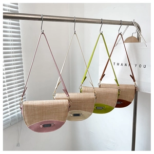 Detailed view of four woven straw saddle bags in various colors hanging on hooks