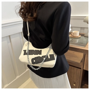 Close-up of LINN CIRCLE embroidered white underarm bag with silver chain strap on model