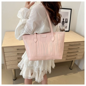 Detail of light pink zebra print tote bag shown on a shoulder in a warm interior