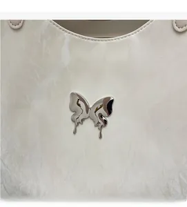 Detail of silver bow emblem on cream tote bag with marble texture and fine stitching