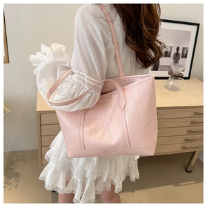 Detail of light pink tote bag featuring a subtle vertical texture and elegant leather tag