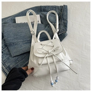 Close-up of white PU leather mini backpack featuring bow detail and beaded drawstring