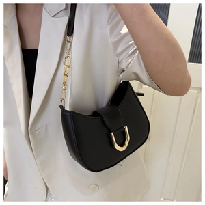 Detail of black crescent shoulder bag with gold U-shaped buckle and metal chain strap