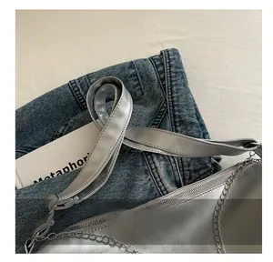 Detail of silver metallic textured handbag with wide strap and silver chain accent