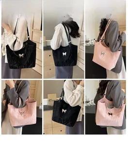 Detail view of large butterfly tote bags in black and pink with metallic bow accents